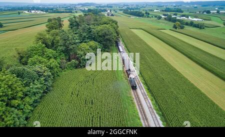 Luftaufnahme einer Dampflokomotive an einem wunderschönen Sommertag durch eine fruchtbare Farmlandschaft reisen Stockfoto