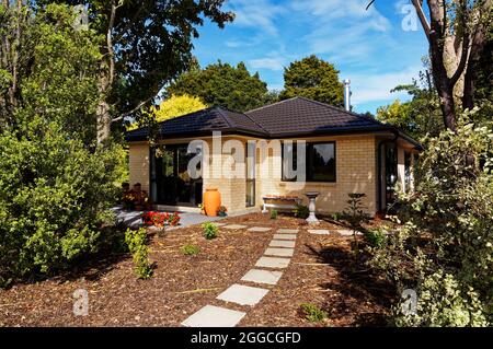 Den Gartenweg hinauf. Ein Gartenweg aus Pflastersteinen, die in Mulch voneinander getrennt sind. Stockfoto