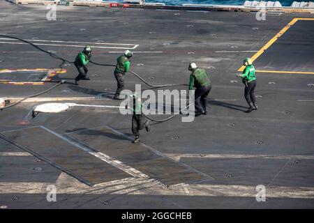 210829-N-CW176-1024 ARABIAN SEA (AUG 29, 2021) – Matrosen handhaben einen festhafenden Draht auf dem Flugdeck des Flugzeugträgers USS Ronald Reagan (CVN 76) im Arabischen Meer, 29. August. Ronald Reagan ist das Flaggschiff der Carrier Strike Group 5 und wird im Einsatzgebiet der 5. US-Flotte zur Unterstützung von Marineoperationen eingesetzt, um die maritime Stabilität und Sicherheit in der Zentralregion zu gewährleisten. Verbindung des Mittelmeers mit dem Pazifik durch den westlichen Indischen Ozean und drei strategische Engpässe. (USA Navy Foto von Mass Communication Specialist Seaman Matthew Mitchell) Stockfoto