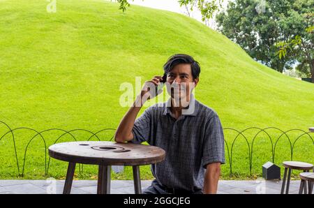 Hispanic Mann benutzt Handy im Park Stockfoto