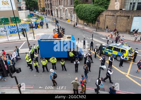 London, Großbritannien. August 2021. Die Polizei umzingeln zwei Demonstranten auf einem Transporter, der während eines Protestes zur Ausrottung der Rebellion in London als Teil einer Straßensperre benutzt wurde. Kredit: SOPA Images Limited/Alamy Live Nachrichten Stockfoto