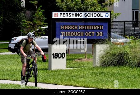 Orlando, Usa. August 2021. Ein Junge fährt mit dem Fahrrad an einem Schild an der Pershing School in Orlando vorbei, auf dem er darauf hinweist, dass bis zum 30. Oktober 2021 Gesichtsmasken für Schüler erforderlich sind. Am 27. August 2021 warf ein Richter in Florida das Verbot von Gesichtsmasken-Mandaten von Gouverneur Ron DeSantis in Schulen aus. Kredit: SOPA Images Limited/Alamy Live Nachrichten Stockfoto