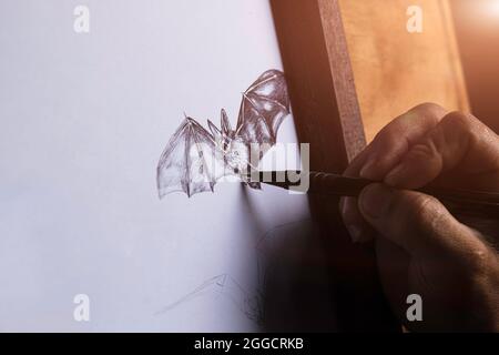 Mann Hand Zeichnung eine Fledermaus auf weißem Papier. Stockfoto