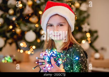 Kleines Mädchen in santa Hut mit Girlande Stockfoto