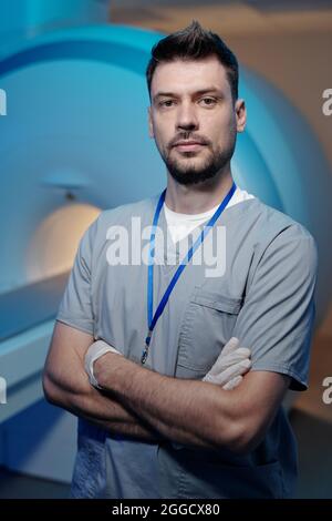 Junger erfolgreicher Arzt in Uniform, der gegen medizinische Geräte für Magnetresonanztomographie-Scans steht Stockfoto