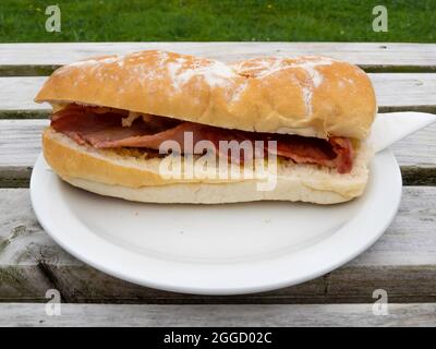 Mittags Snack auf einem Außentisch Bacon in einem weichen weißen Rolle Stockfoto