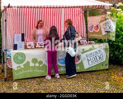 Eine Frau, die auf einem Bauernmarkt in der ummauerten Rose Garden Wynyard Hall Platz nahm und in der Melkstube Käse serviert Stockfoto