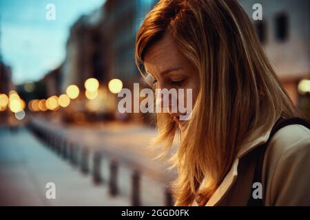 Porträt einer Frau in der nächtlichen Stadtstraße mit Bokeh-Lichtern Stockfoto