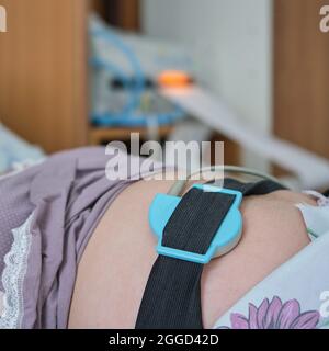 Eine Schwangere gebiert in einem Krankenhaus mit einem Tropf und einem Kardiotokographen Stockfoto