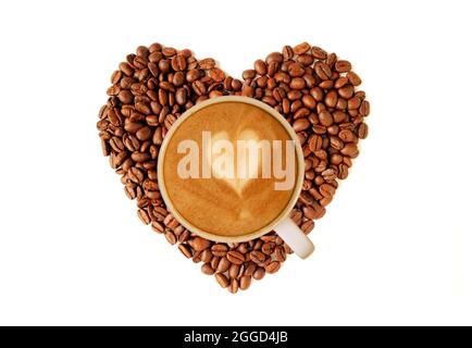 Ein Cappuccino-Kaffee auf einer Heap von herzförmigen gerösteten Kaffeebohnen Stockfoto