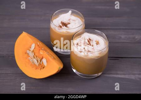 Zwei Gläser Kürbis Latte mit Kürbisscheiben auf dunklem Grund. Stockfoto