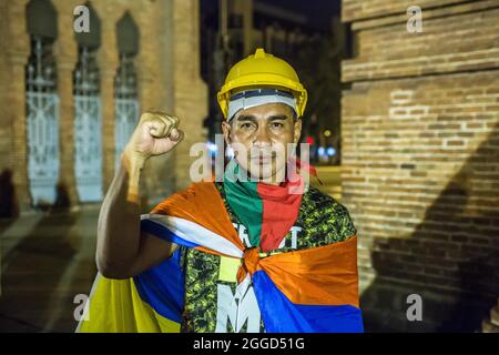 Barcelona, Spanien. August 2021. Erste Verteidigungslinie bei den regierungsfeindlichen Protesten in Kolumbien wird Ricardo 'Profe' mit der Faust gesehen. Rund 200 Menschen haben vor dem Arc de Triomf in Barcelona gegen die 6402 außergerichtlichen Tötungen demonstriert, die von der Armee im Zusammenhang mit dem bewaffneten Konflikt in Kolumbien begangen wurden, ein Phänomen, das als „falsche positive“ bekannt ist. Bild: DAX Images/Alamy Live News Stockfoto