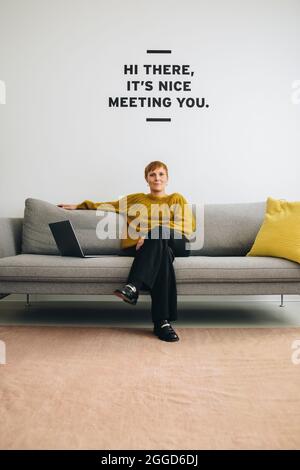 Frau sitzt auf dem Sofa in der Bürolobby. Selbstbewusste Geschäftsfrau in der Lobby. Stockfoto