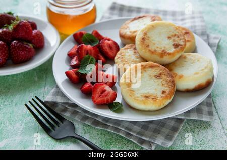 Quark-Pfannkuchen, Ricotta-Fritten auf Keramikplatte mit frischer Erdbeere. Gesundes und leckeres Frühstück am Morgen. Stockfoto