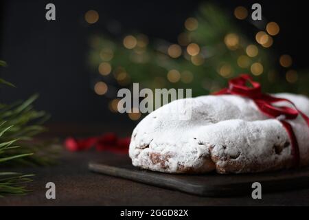 Traditionelles, mit Stollen dekoriertes rotes Festseil, immergrüne Äste und Girlande auf einem braunen Festtisch. Weihnachtsfeiertage traditionelle Leckereien. Stockfoto