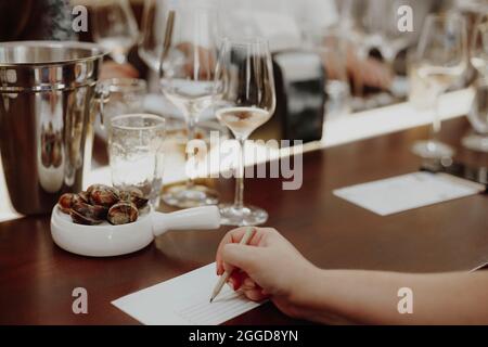 Gläser mit verschiedenen Weinsorten von menschlicher Hand schreiben Notizen über Weingläser im Hintergrund. Degustationswein Stockfoto