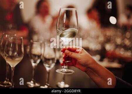 Gläser mit verschiedenen Weinsorten und menschlichen Händen, die Weingläser im Hintergrund halten. Degustationswein Stockfoto