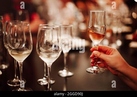 Gläser mit verschiedenen Weinsorten und menschlichen Händen, die Weingläser im Hintergrund halten. Degustationswein Stockfoto