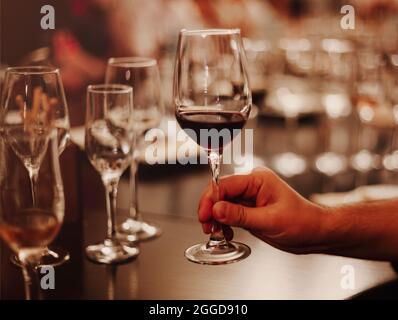 Gläser mit verschiedenen Weinsorten und menschlichen Händen, die Weingläser im Hintergrund halten. Degustationswein Stockfoto