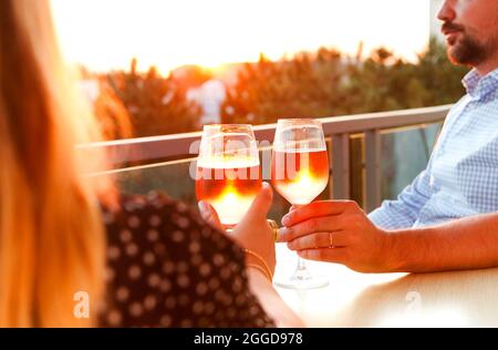 Pärchen essen auf der Terrasse mit Rosenwein bei Sonnenuntergang Stockfoto