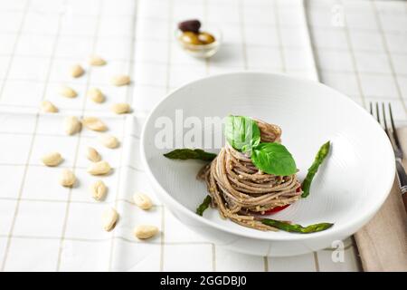 Vollkornspaghetti mit Olivenpesto und Mandel, verziert mit Spargel Stockfoto