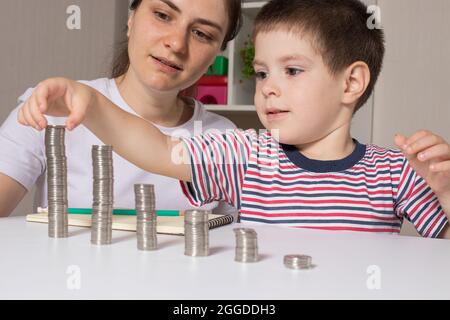 Mutter und Kind lernen finanzielle Bildung für Kinder, um zu investieren. Geld, Münzen, Einkommenswachstum und Kauf von Aktien. Stockfoto