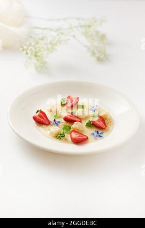 Joghurt und Ingwerbällchen in Vervain-Sauce, garniert mit Erdbeere und Kaffee Stockfoto