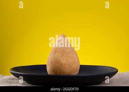 Gebratener Coxinha auf schwarzem Teller mit gelbem Hintergrund. Stockfoto