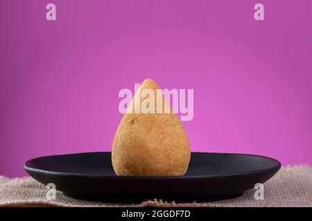 Coxinha auf schwarzem Teller mit rosa Hintergrund. Stockfoto