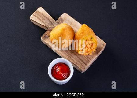 Coxinha auf Holzbrett mit schwarzem Hintergrund. Stockfoto