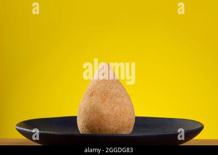 Gebratener Coxinha auf schwarzem Teller mit gelbem Hintergrund. Stockfoto