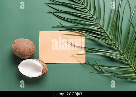 Komposition mit leerer Karte, Kokosnüssen und Palmblatt auf farbigem Hintergrund Stockfoto