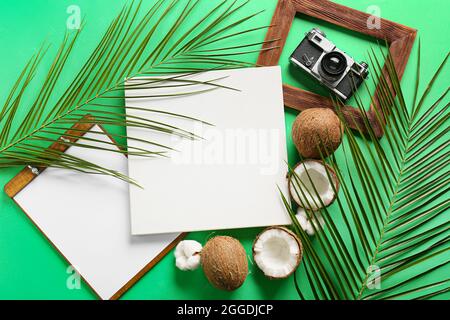 Komposition mit leerem Poster, Zwischenablage, Kokosnüssen und Fotokamera auf farbigem Hintergrund Stockfoto