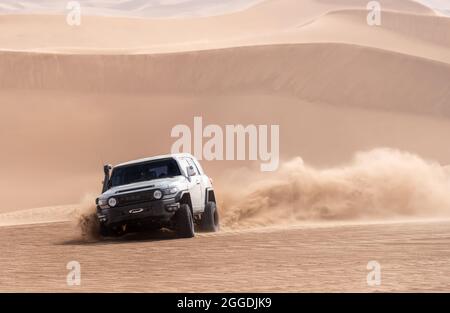 Ein Auto oder suv treibt einen Sand und spritzt Sand auf Luft und um in Dasht e lut oder sahara Wüste. ADS Raum Stockfoto