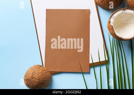 Komposition mit leerer Karte und reifen Kokosnüssen auf farbigem Hintergrund Stockfoto