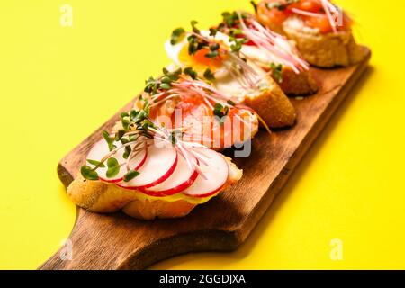 Verschiedene Bruschettas mit Mikrogrün auf farbigem Hintergrund, Nahaufnahme Stockfoto