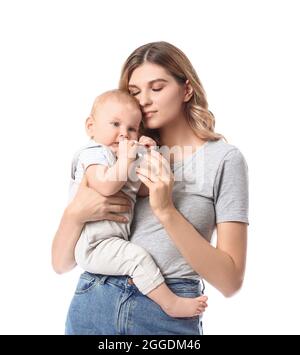 Junge Mutter, die ihrem niedlichen Baby Wasser auf weißem Hintergrund gibt Stockfoto