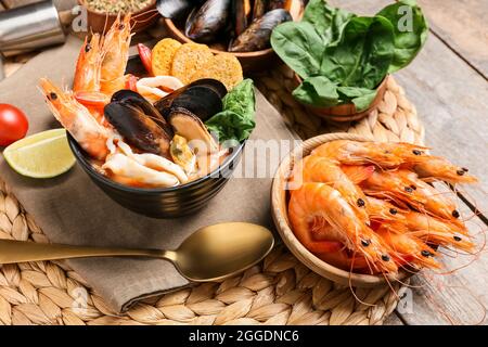 Schüssel mit leckerer Cacciucco-Suppe und Zutaten auf Holzboden Stockfoto