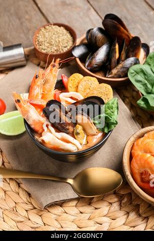 Schüssel mit leckerer Cacciucco-Suppe und Zutaten auf Holzboden Stockfoto