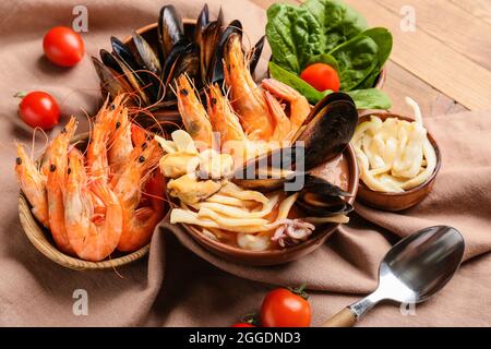 Schüssel mit leckerer Cacciucco-Suppe und Zutaten auf Holzboden Stockfoto