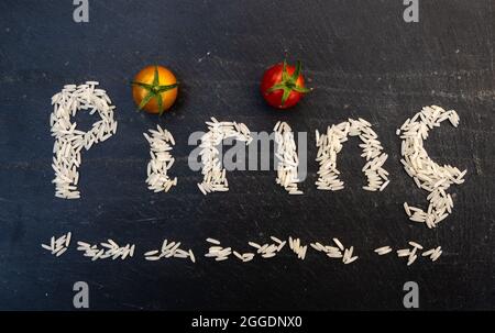 Türkisches Wort pirinç geschrieben von weißen Reiskörnern auf einem schwarzen Schiefertafel Stockfoto