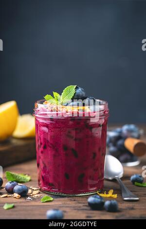 Violetter Heidelbeer-Smoothie in einem Glasglas, dunkelblauer Kreidegrund mit Kopierraum. Veganer Smoothie mit Superfood Stockfoto