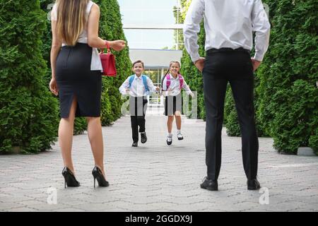 Eltern treffen ihre kleinen Kinder nach der Schule Stockfoto