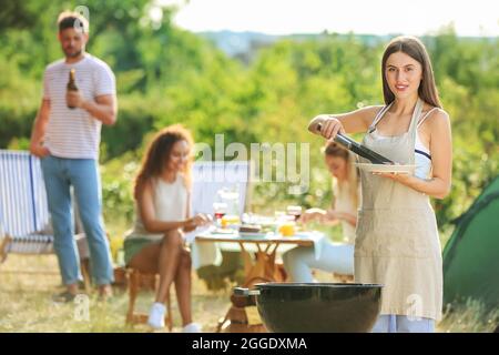 Junge Frau kocht Essen auf Grill im Freien Stockfoto