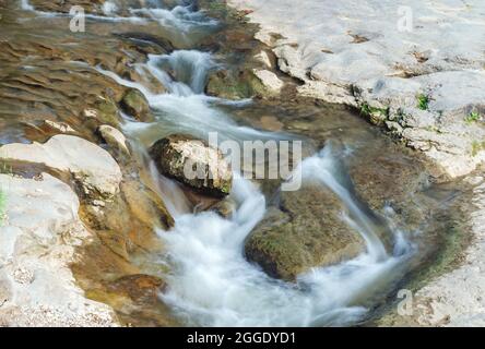 Ein schneller Gebirgsbach fließt durch den Felsen. Nahaufnahme von rauem Wasser im Fluss. Stockfoto