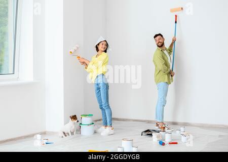 Junges Paar mit niedlichem Hund bei der Reparatur ihres neuen Hauses Stockfoto