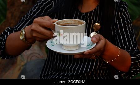 Frau, die eine Tasse schwarzen Kaffee in einer elfenbeinweißen Keramikschale trinkt Stockfoto