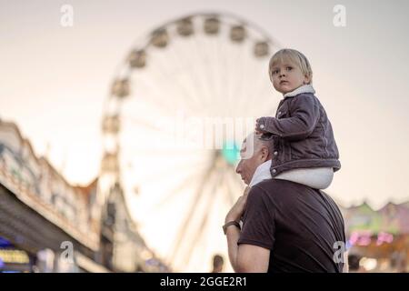 Glücklicher Vater mit seinem kleinen huckepack Sohn in einem Vergnügungspark Stockfoto