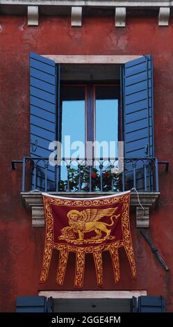 Traditioneller, farbenfroher Balkon mit aufgehängter Flagge und Wappen, venedig, italien Stockfoto