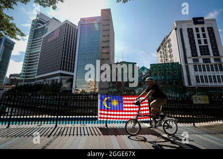 Ein Radfahrer fährt bei den Feierlichkeiten zum 64. Nationalfeiertag in Kuala Lumpur an einer malaysischen Flagge vorbei.Malaysia feiert seinen 64. Unabhängigkeitstag jährlich am 31. August und erinnert an die malaysische Unabhängigkeitserklärung vom 31. August 1957. Stockfoto